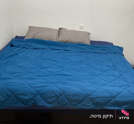 חדר שינה עם מיטה זוגית, כריות ושמיכה כחולה